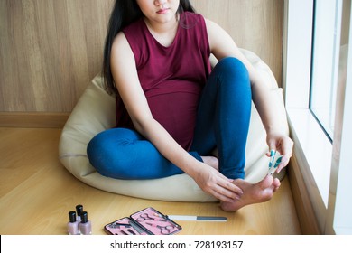 Pregnant Woman Gets A Nail Manicure On Bean Bag Chair. Trimming Toenails.