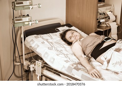 A pregnant woman gives birth in a hospital with a drip and a CTG machine. A woman on a clinic bed during labor pains.