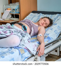 A pregnant woman gives birth in a hospital with a drip and a CTG machine. Woman on clinic bed with anesthesia at the time of labor pains.