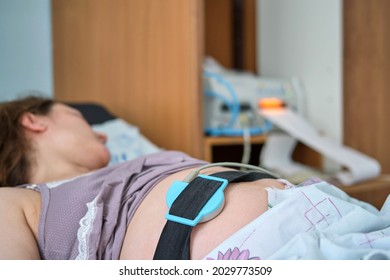 A pregnant woman gives birth in a hospital with a drip and a CTG machine