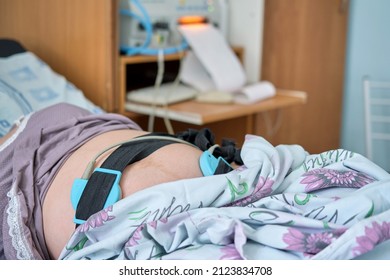 A pregnant woman gives birth in a hospital with a drip and a cardiotocograph machine. Woman on clinic bed with anesthesia at the time of labor pains. - Powered by Shutterstock