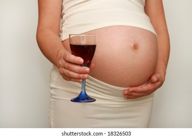 Pregnant woman with glass of red wine. Nine month. Third trimester.