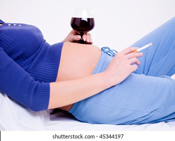 Pregnant woman with a glass of wine and cigarette in hand