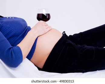 Pregnant woman with a glass of wine on the stomach