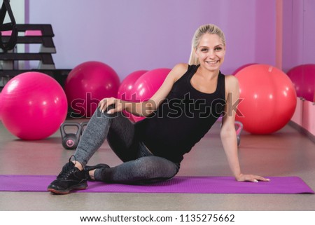 Pregnant woman in the gym sitting on the mat relaxing after training to keep fit yourself