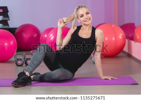 Pregnant woman in the gym sitting on the mat relaxing after training to keep fit yourself