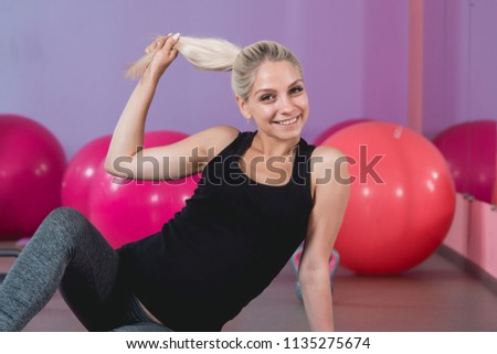 Pregnant woman in the gym sitting on the mat relaxing after training to keep fit yourself