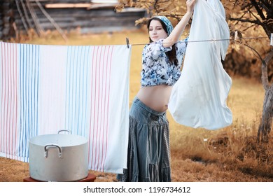 Pregnant Woman Hanging Sheets On The Rope For Drying