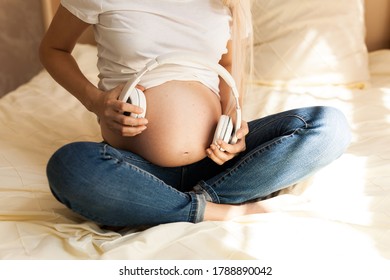 Pregnant Woman With Headphones On Her Stomach. Future Baby Listens To Music. Therapy, Healthcare, Motherhood Concept