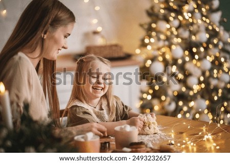 pregnant woman and her 3 year old daughter near the New Year tree in kitchen cooking. Noise blurred toned vintage film grain image	