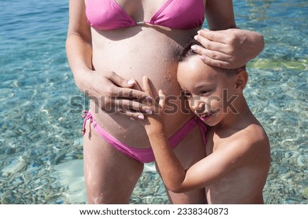 Pregnant woman and her child standing in the sea. Boy holding his mother for the belly. Adriatic sea. Child about 6 yearsold.