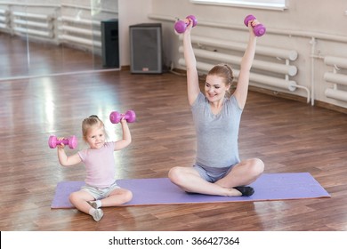 Pregnant woman with her first kid daughter doing gymnastics in living room.  - Powered by Shutterstock