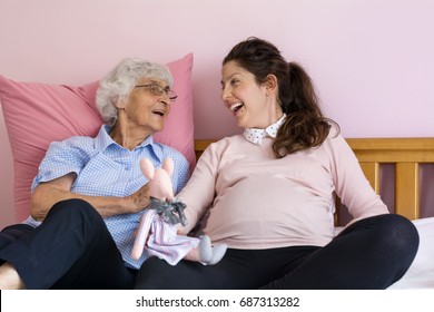 Pregnant Woman With Her Grandmother Having Fun  In A Baby Room