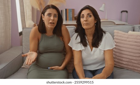 Pregnant woman with her mother sitting on a couch in an interior living room, expressing emotions and love, highlighting a family moment indoors at home. - Powered by Shutterstock