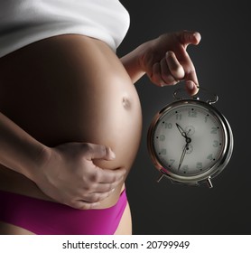 Pregnant woman holding a clock at her belly - Powered by Shutterstock