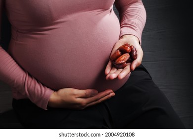 Pregnant Woman Holding Dried Date Palm Fruit On Black Background