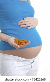 Pregnant Woman Holding A Handful Of Dried Fruit (apricots)