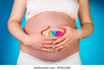 Pregnant Woman Holding Hands In IVF Lettering On A Blue Background.