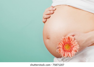 Pregnant woman holding her belly and flower