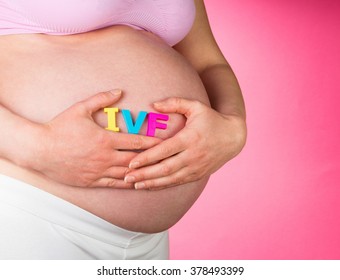 Pregnant Woman Holding IVF Lettering On A Pink Background