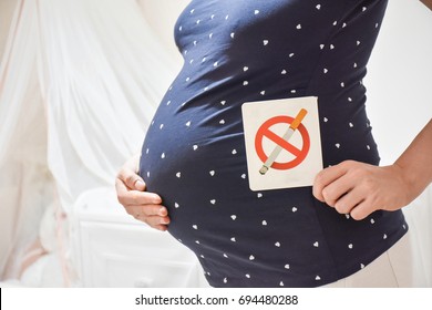 Pregnant Woman Holding No Smoking Sign Label On Belly In Baby Bedroom. Unhealthy Concept.