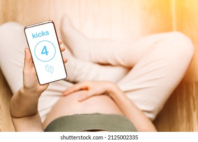 Pregnant woman holding a phone with an app to track baby kicks. Pregnancy apps, gadgets, moves and kicks tracking background