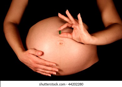 A Pregnant Woman Holding A Prenatal Vitamin.