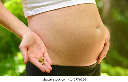 Pregnant Woman Holding Prenatal Vitamins By Stomach