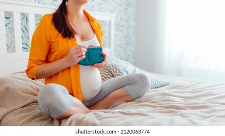 Pregnant Woman Holding Purse In Bed. Pregnant Woman Counting Money In Purse.