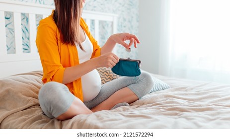 Pregnant Woman Holding Purse In Bed. Pregnant Woman Counting Money In Purse, Putting Coins Into Purse.