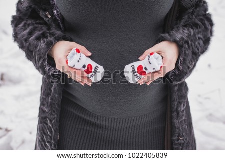 Pregnant woman holding small baby socks