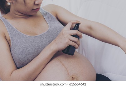 Pregnant Woman Holding  Spray Bottle Of Mosquito Repellent. Young Female Spraying Mineral Water Or Perfume On Her Hands, Treatment, Skin, Beauty, Cosmetic, Makeup, Healthy, Lifestyle Concept.