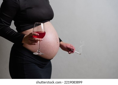 A Pregnant Woman Is Holding Wine In Her Hands And Smoking A Cigarette. The Concept Of Harm Of Smoking And Alcohol Consumption During Pregnancy. High Quality Photo