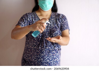 Pregnant  woman holds bottle of hand sanitizer to clean her hands. Concept : Health care during pregnancy and epidemic of coronavirus or Covid-19  and other germs .                              