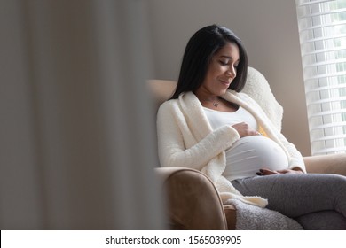 A pregnant woman holds her belly in antipation of her growing family.