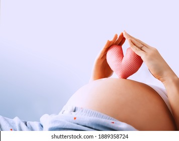 Pregnant woman holds in palms symbol in heart shape. Loving mom waiting of a baby. Concept of maternity, parenting, prepare and expect. Happy expectant mother during pregnancy.