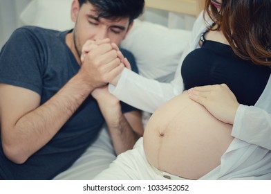 Pregnant woman and husband. Both are planning the birth of the child. Kiss to show love and caring