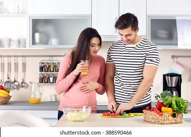 Pregnant woman with husband cooking food in kitchen - Powered by Shutterstock