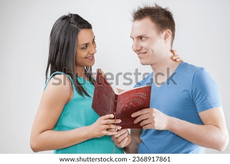 Pregnant woman and husband explore a booklet, selecting names. They uphold longstanding traditions and review the first ultrasound images, saved in their unborn child's album