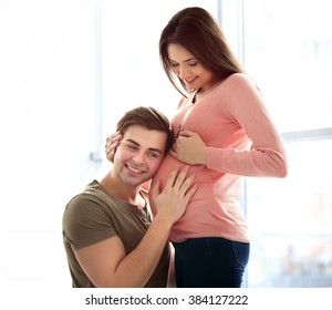 Pregnant woman with husband in front of the window