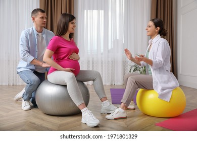 Pregnant woman with husband and midwife in gym