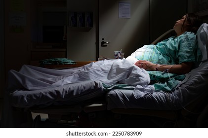 Pregnant woman in labor laying in hospital bed with rays of light shining on belly stomach in maternity ward - Powered by Shutterstock