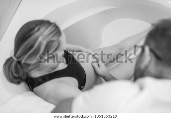 Pregnant woman in labour, labor, \
during childbirth, giving birth, birthing pool, water\
bath\
