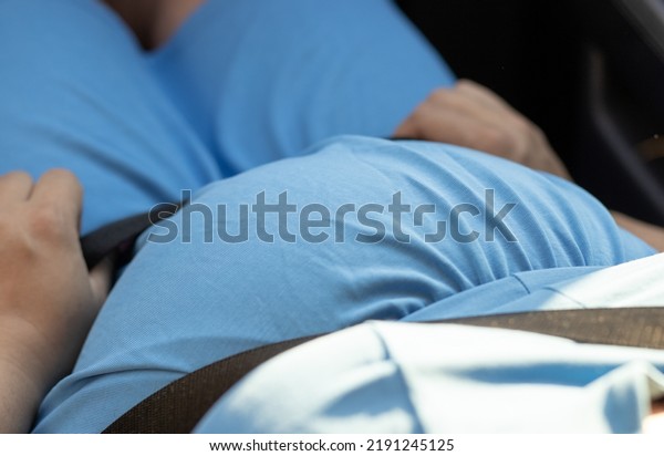 pregnant woman last third trimester wear safety seat\
belt in the car.fasten belt road trip drive car,travel tourism\
concept.female wearing blue color dress.future mother,pregnancy\
maternity love care