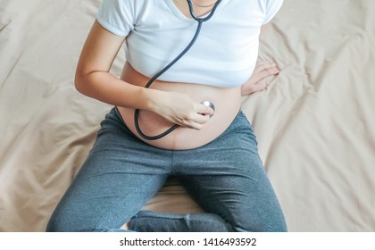 Pregnant Woman Listen To Baby Heart Beat With Doctor Stethoscope