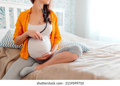 Pregnant Woman Listening To Baby's Heartbeat With Stethoscope