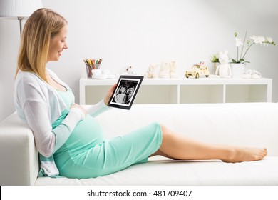 Pregnant woman looking at her babies first sonography results on tablet