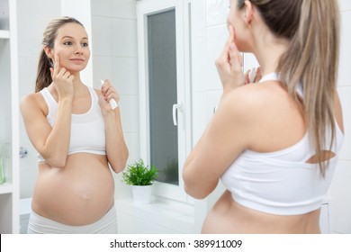 Pregnant woman in looking into bathroom mirror - Powered by Shutterstock