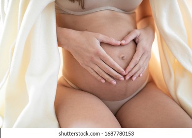 Pregnant woman is lying on the bed. She is expecting her baby. Young mom. Pregnancy and woman's health. Genicology and medicine. Mom's health. Parenthood and consultations of a geneticist. Motherhood.