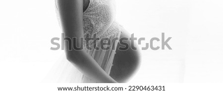 Pregnant woman maternity artistic photoshoot. Pregnancy profile portrait showing beautiful big belly baby bump third trimester. Woman expecting baby shot profile panoramic banner in black and white.